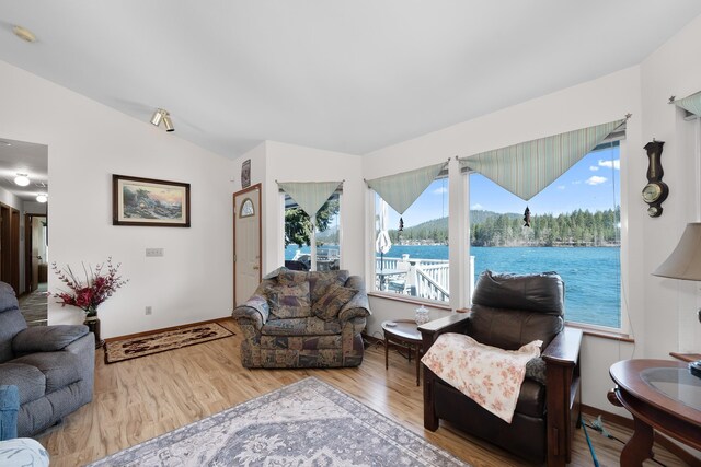 living area with vaulted ceiling, wood finished floors, a water view, and a healthy amount of sunlight