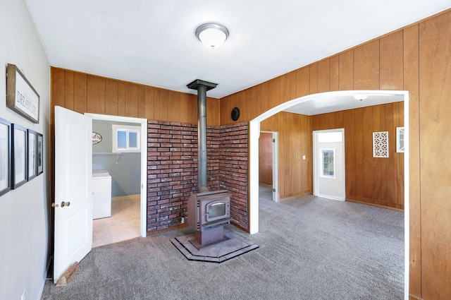 8323 W Mission Ave, Spokane, WA 99224 - unfurnished living room featuring arched walkways, wood walls, a wood stove, and carpet