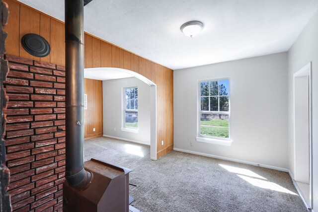 8323 W Mission Ave, Spokane, WA 99224 - carpeted empty room featuring arched walkways, wood walls, and baseboards