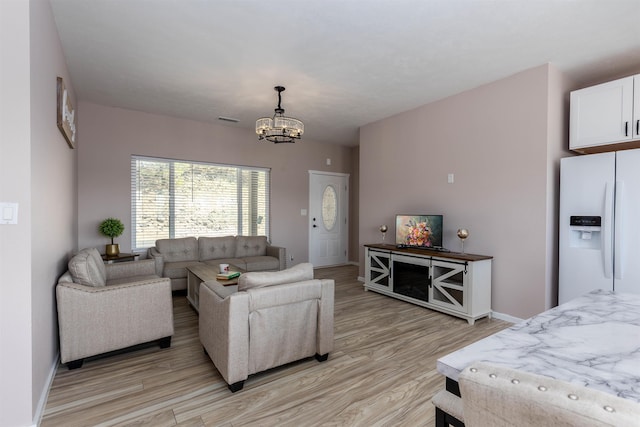 living area with baseboards, a chandelier, visible vents, and light wood-type flooring