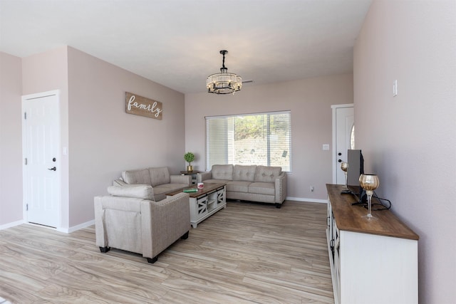 living room featuring baseboards, an inviting chandelier, and light wood-type flooring