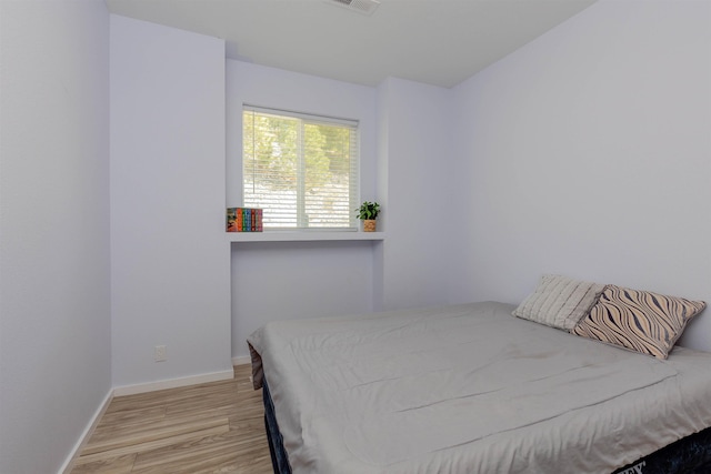 bedroom featuring visible vents, baseboards, and wood finished floors