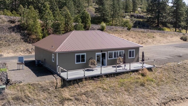 back of property featuring a wooden deck, central air condition unit, and metal roof