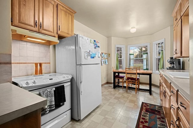 kitchen with decorative backsplash, white appliances, light floors, light countertops, and under cabinet range hood