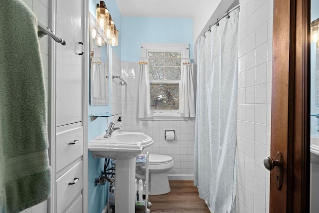 bathroom with a shower with shower curtain, tile walls, toilet, and wood finished floors