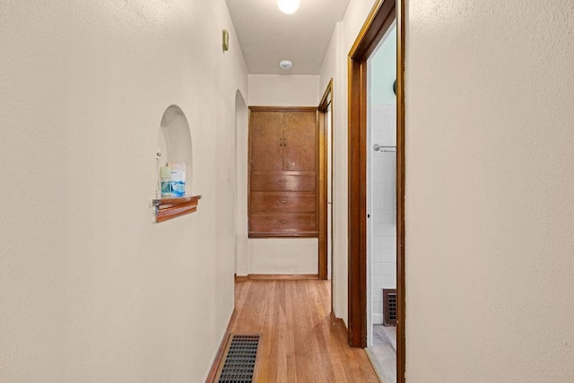 hallway featuring light wood-style flooring and visible vents