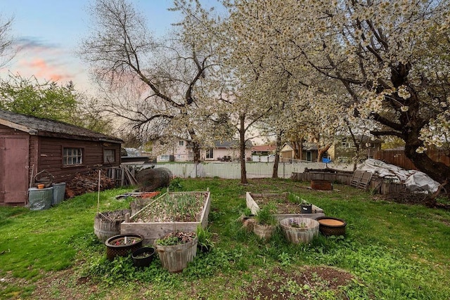 view of yard featuring a garden, fence, an outbuilding, and a storage unit