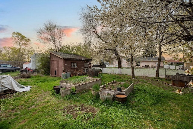 view of yard featuring fence, a garden, and an outbuilding