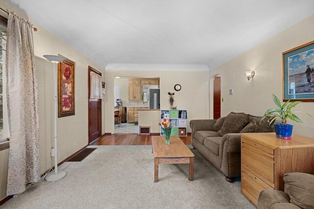 carpeted living area featuring arched walkways, visible vents, and baseboards