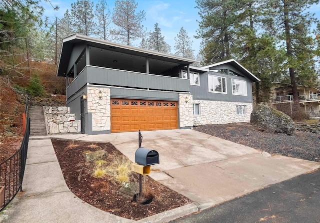 7415 N Birch Ct, Spokane, WA 99208 - view of front of property featuring stone siding, a garage, a balcony, and driveway