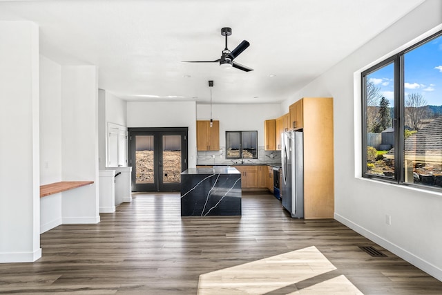 kitchen featuring a wealth of natural light, dark countertops, freestanding refrigerator, and baseboards