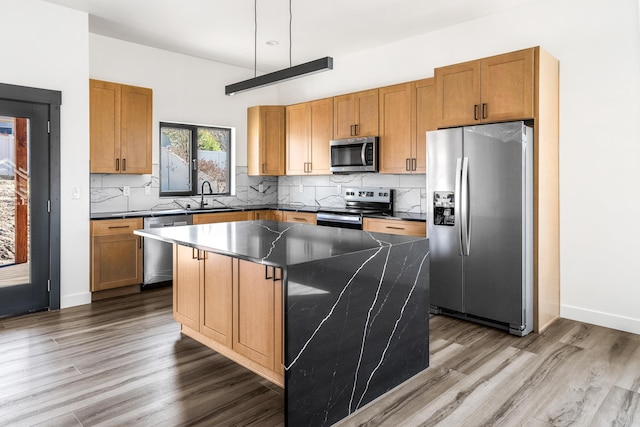kitchen with dark wood-type flooring, dark countertops, stainless steel appliances, and a sink