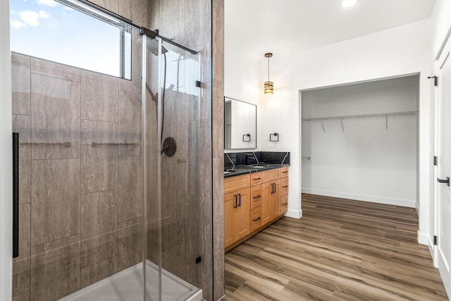 bathroom featuring vanity, a stall shower, baseboards, wood finished floors, and a spacious closet