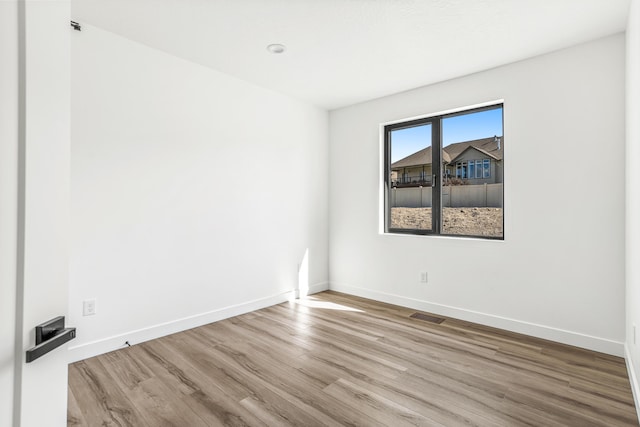 unfurnished room featuring visible vents, wood finished floors, and baseboards