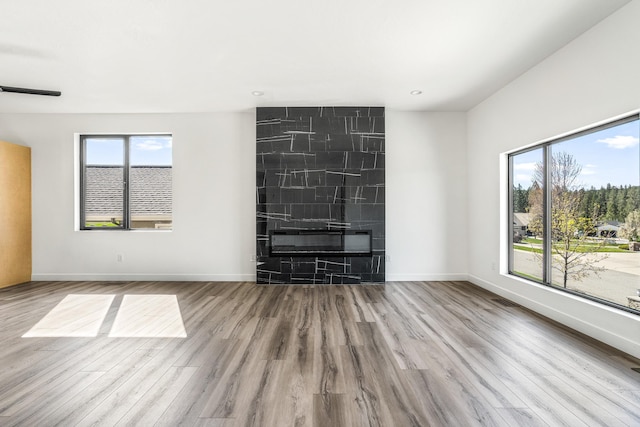 unfurnished living room with baseboards, wood finished floors, and plenty of natural light
