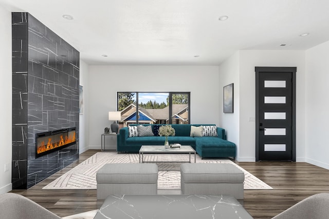 living area featuring wood finished floors, a tiled fireplace, and baseboards
