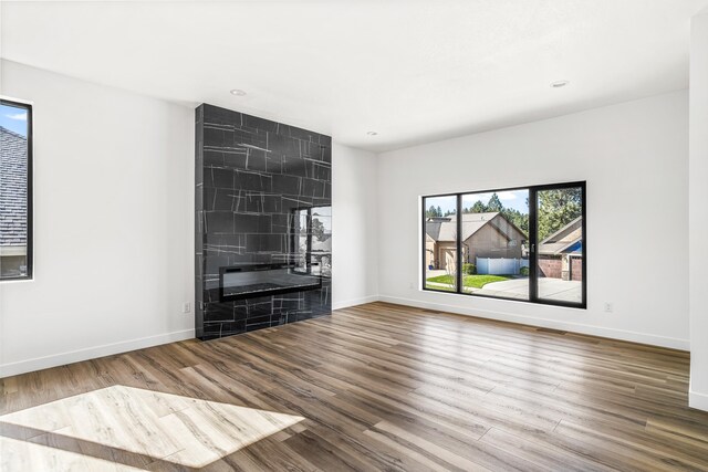 unfurnished living room with recessed lighting, wood finished floors, and baseboards