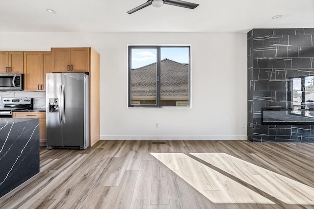 kitchen featuring brown cabinetry, stainless steel appliances, ceiling fan, light wood finished floors, and baseboards