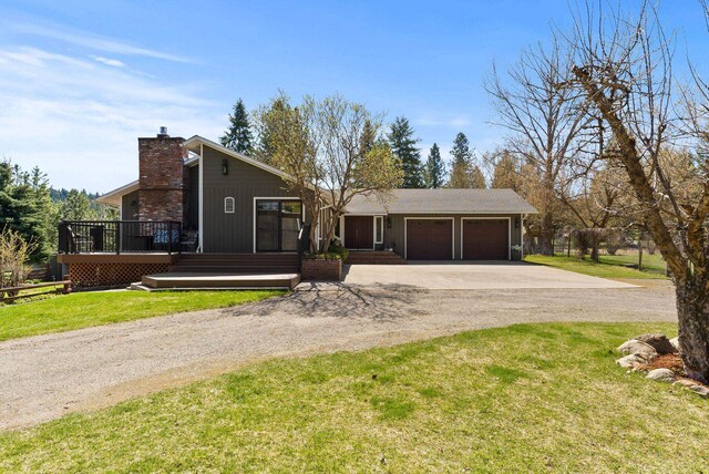 view of front of house with concrete driveway, a front lawn, a chimney, and a garage
