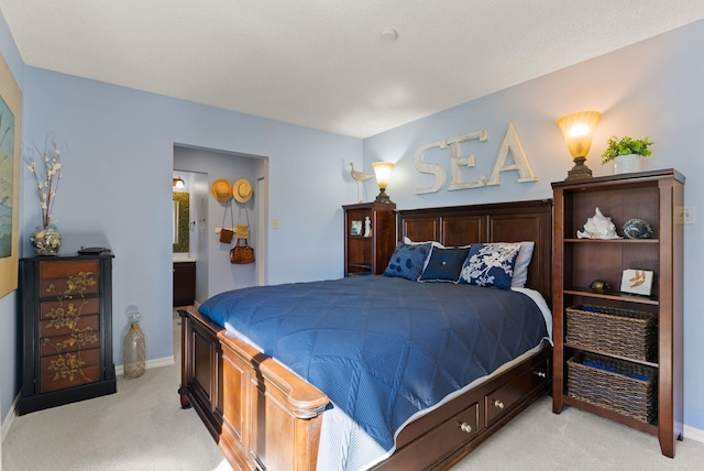 bedroom with ensuite bath, baseboards, and light colored carpet