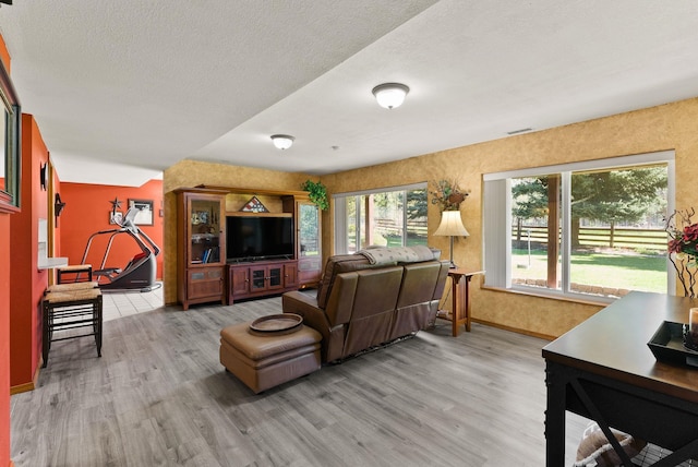 living room featuring a textured ceiling, wood finished floors, visible vents, and baseboards
