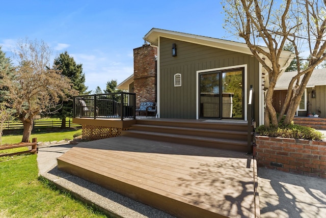 rear view of house featuring fence, a wooden deck, a lawn, and board and batten siding
