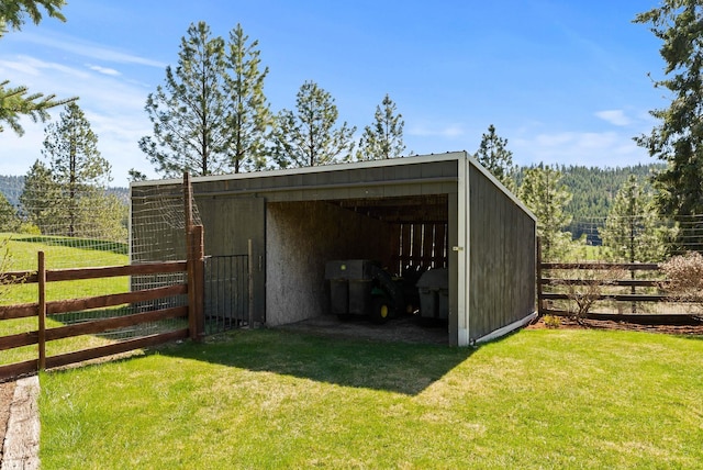 view of pole building featuring a lawn and fence