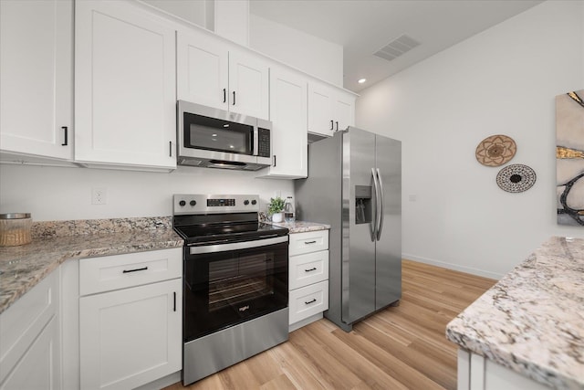 kitchen with light wood-style flooring, visible vents, white cabinetry, light stone counters, and appliances with stainless steel finishes