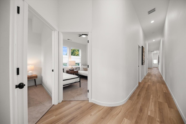 hallway featuring light wood-type flooring, baseboards, and visible vents