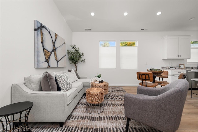 living room with recessed lighting, light wood-style flooring, visible vents, and baseboards