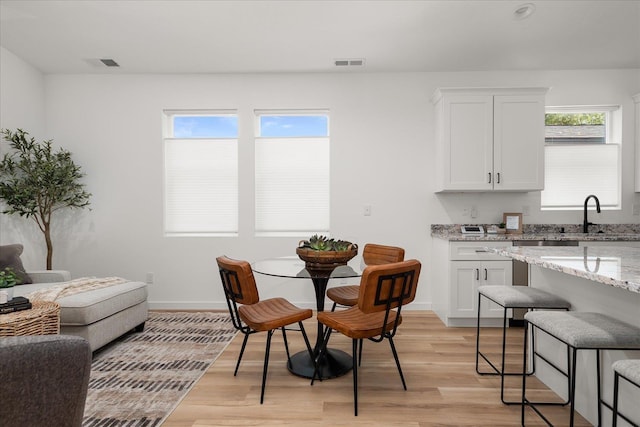 dining area featuring light wood-type flooring, visible vents, and baseboards