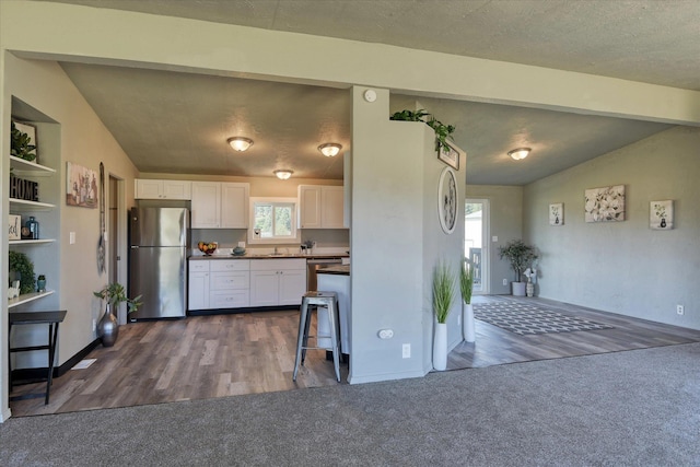kitchen featuring stainless steel appliances, dark carpet, white cabinetry, and dark countertops