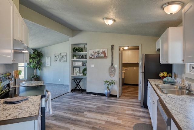 kitchen with under cabinet range hood, stainless steel appliances, vaulted ceiling, a textured ceiling, and white cabinetry