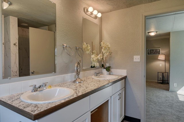 full bath featuring a textured wall, a sink, and double vanity