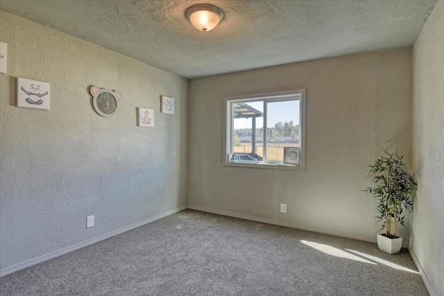 carpeted spare room featuring baseboards, a textured wall, and a textured ceiling