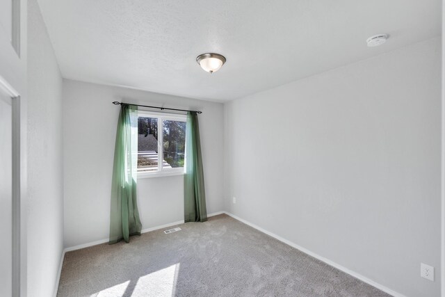 carpeted spare room with baseboards and visible vents