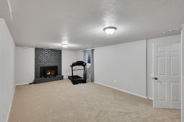 exercise area with a textured ceiling, visible vents, carpet, baseboards, and a brick fireplace