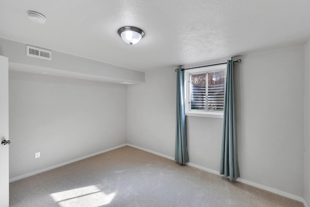 unfurnished room featuring baseboards, visible vents, carpet, and a textured ceiling