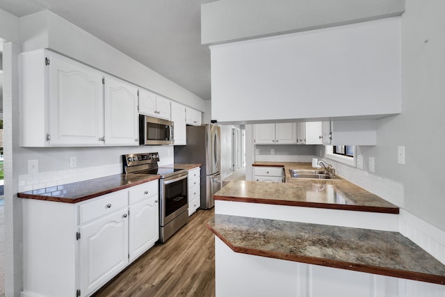 kitchen with wood finished floors, a sink, white cabinetry, and appliances with stainless steel finishes