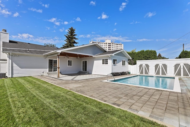 outdoor pool with a ceiling fan, fence, an outbuilding, a yard, and a patio