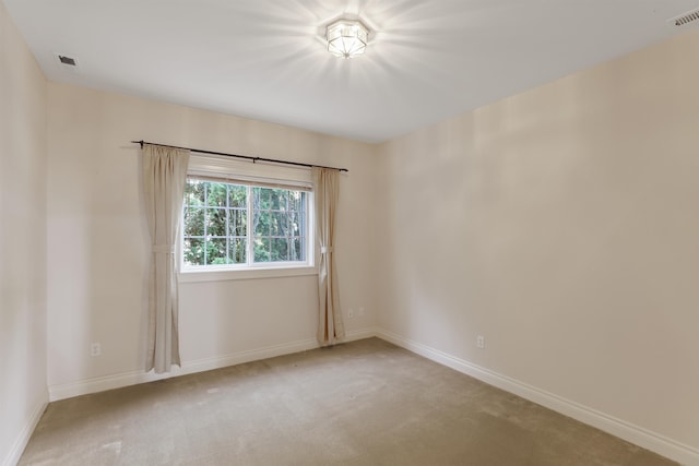 unfurnished room with carpet floors, visible vents, and baseboards