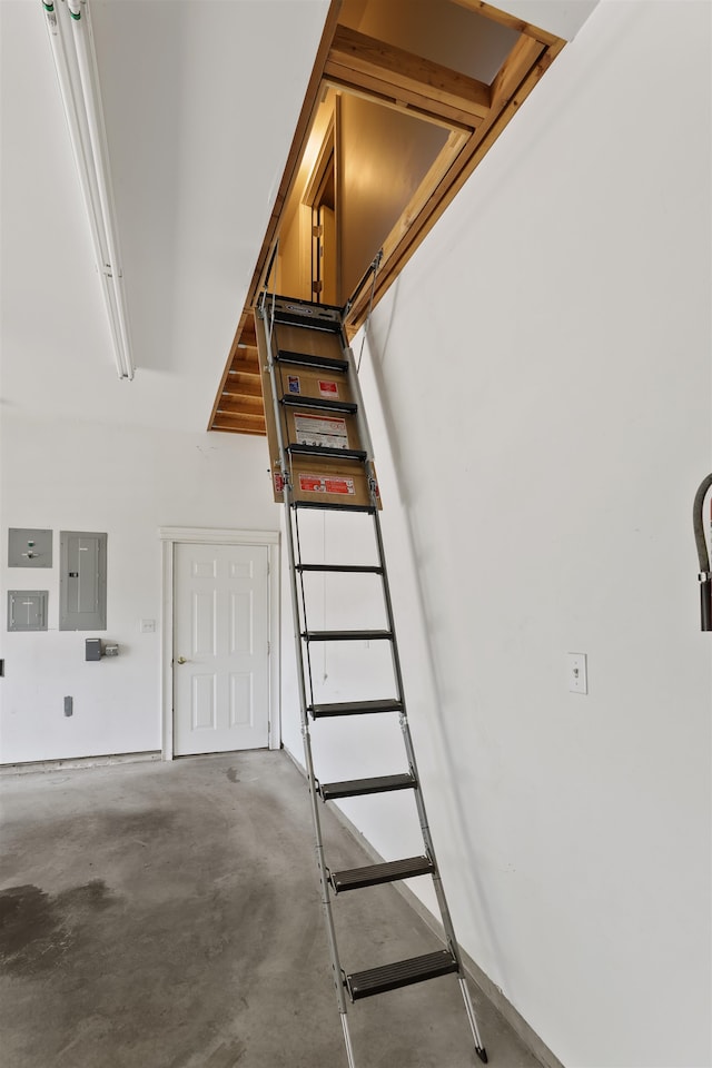 stairs featuring unfinished concrete floors and electric panel