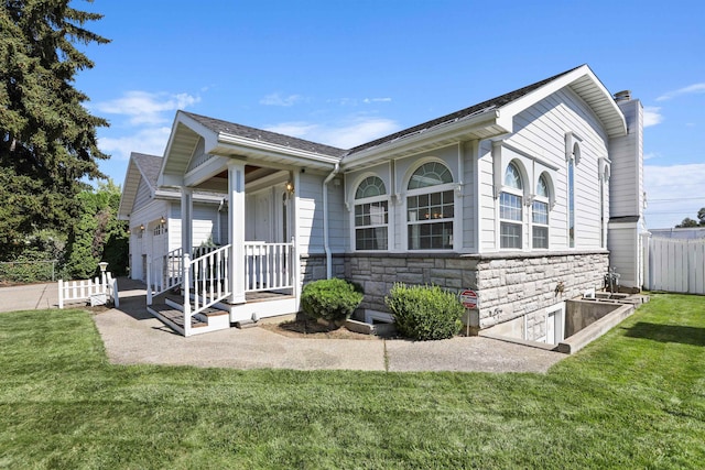 ranch-style home featuring a chimney, a front lawn, fence, and stone siding