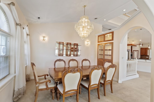 dining space with an inviting chandelier, baseboards, arched walkways, and light colored carpet