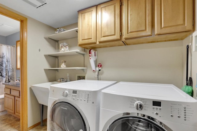 washroom with washing machine and clothes dryer, visible vents, and cabinet space