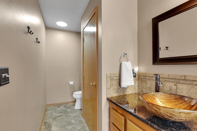 bathroom with toilet, vanity, and baseboards