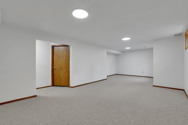 finished basement with visible vents, baseboards, and light colored carpet