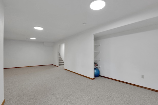 finished below grade area with carpet, baseboards, and stairway