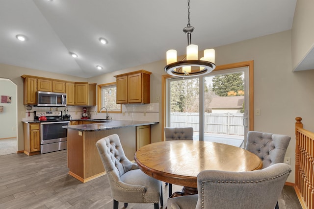 dining area featuring vaulted ceiling, light wood-style flooring, and an inviting chandelier