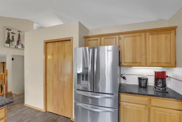 kitchen with vaulted ceiling, dark stone countertops, wood finished floors, backsplash, and stainless steel refrigerator with ice dispenser